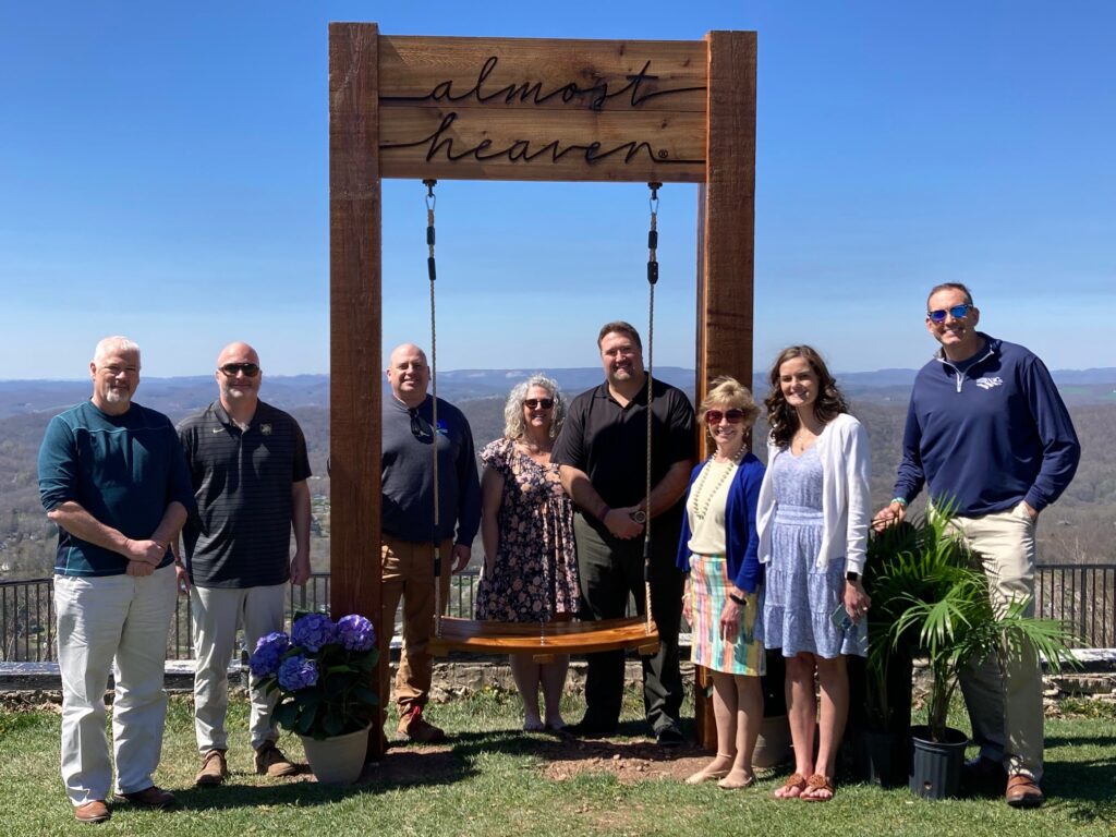Princeton, Bluefield, and Mercer County leaders standing around the "almost heaven" wooden swing at the East River Mountain Overlook.